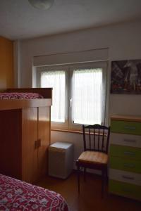 a bedroom with a bed and a chair and two windows at Apartamento Edificio Vistamar - Playa de Barro in Barro de Llanes