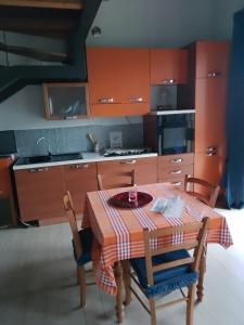 une cuisine avec une table et des chaises et une cuisine avec des armoires orange dans l'établissement Cascina Amrit CAV, à Borghetto Lodigiano