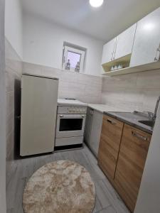 una cocina con electrodomésticos blancos, fregadero y alfombra en Konak, en Plav