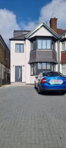 un coche azul estacionado frente a una casa en Star London Finchley Lane 3-Bed Residence with Garden, en Hendon