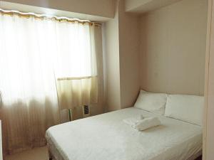 a bedroom with a white bed with a window at Minimalist Condotel at SMDC Sea Residences in Manila