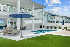 a patio with chairs and an umbrella in front of a house at Luna Light ~ Waterfront ~ Pool ~ Dock ~ Views in Marathon