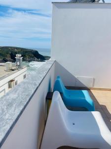 a bench on a balcony with a view of the ocean at Sunset Beach House in Zambujeira do Mar