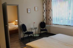 um quarto de hotel com duas cadeiras e uma cama e um espelho em Airport Hotel Jägerhof Weeze em Weeze