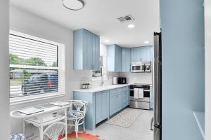 a kitchen with blue cabinets and a table with chairs at Oasis: Hot tub, fire pit, fun! in Vero Beach