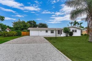 une maison blanche avec un palmier et une allée dans l'établissement Oasis: Hot tub, fire pit, fun!, à Vero Beach