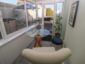 5 Pontardulais Road في ليانيلي: غرفة معيشة مع طاولة زجاجية وكرسي