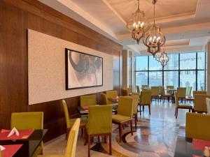 a dining room with tables and chairs and a painting at Al safwah Tower one in Mecca