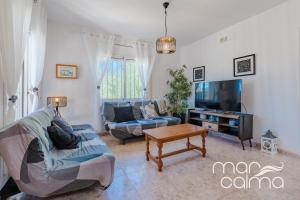 a living room with a couch and a tv at Villa Dolce Relax by MarCalma in Les tres Cales