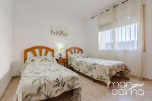 two beds in a room with a table and a window at Villa Dolce Relax by MarCalma in Les tres Cales +26 photos
