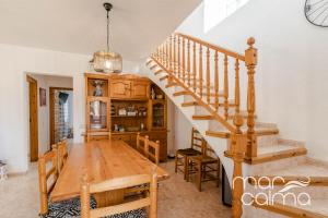 a dining room with a wooden table and stairs at Villa Dolce Relax by MarCalma in Les tres Cales