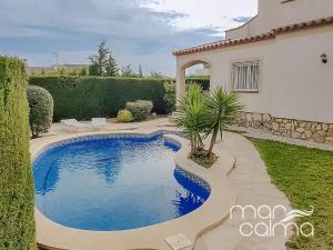 a swimming pool in a yard next to a house at Villa Dolce Relax by MarCalma in Les tres Cales