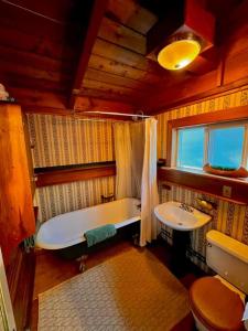 a bathroom with a bath tub and a sink at Nostalgic Downtown Boatbuilder's Cabin - Licensed in Squamish