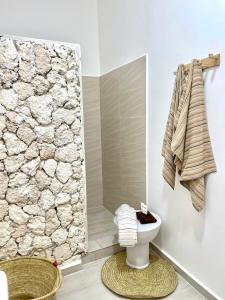 a bathroom with a toilet and a stone wall at Casa DantesVoyage - SPA in Nungwi