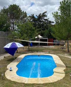a swimming pool with an umbrella and a volleyball at Las toscas casa con piscina in Las Toscas
