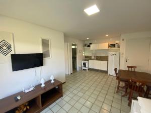 a living room with a table and a television on a wall at Ancorar Flat Resort in Porto De Galinhas