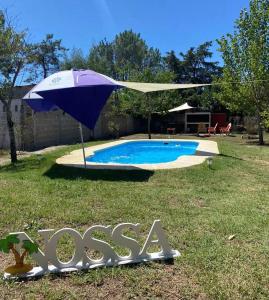 a pool with an umbrella in the yard at Las toscas casa con piscina in Las Toscas