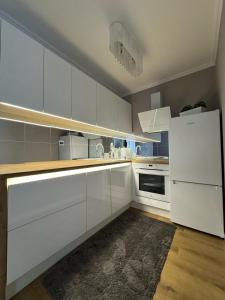 uma cozinha com armários brancos e um frigorífico branco em Apartament Szarotki em Szczecin