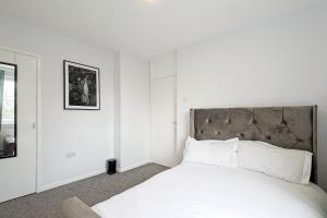 a white bedroom with a large bed with white sheets at EDSPACE in Abbey Wood