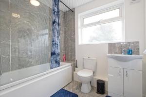 a bathroom with a toilet and a tub and a window at EDSPACE in Abbey Wood