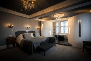 a bedroom with a bed and two chairs and a chandelier at The Alamo Guest House in Glasgow