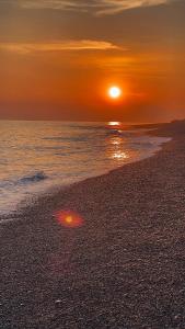 a sunset on a beach with the sun setting at Casa Erika in Bova Marina