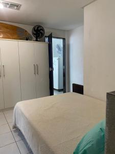 um quarto com uma cama, armários e um frigorífico em Quarto e sala pé na areia em Guarapari