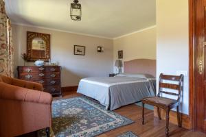 a bedroom with a bed and a chair and a dresser at Quinta de Mourães Casa dos Rododendros in Lever