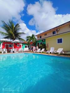 una piscina frente a un hotel con sillas y palmeras en Pousada Maceio, en Maceió