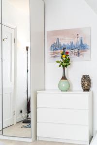 a white cabinet with a vase with flowers on it at Stylish Apartment Near Broadway Theatre in Catford