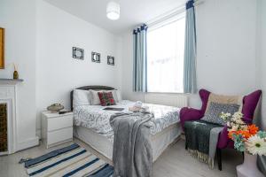a bedroom with a bed and a chair and a window at Stylish Apartment Near Broadway Theatre in Catford