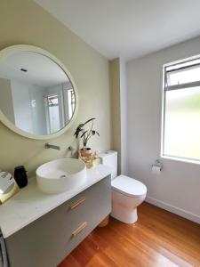 a bathroom with a sink and a toilet and a mirror at Inner City Sunny Bedroom in Auckland