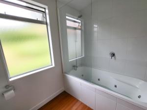 a bathroom with a shower and a tub and a window at Inner City Sunny Bedroom in Auckland