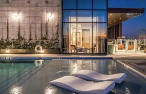 a swimming pool with two white chairs in front of a building at Luxury 2BR Rooftop Pool Austin by Barclé in Austin