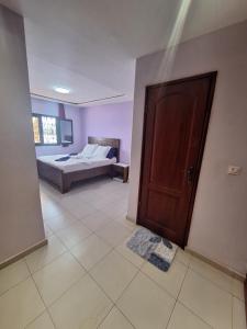 - une chambre avec un lit et une porte en bois dans l'établissement RÉSIDENCE DES 7 COLLINES, à Yaoundé