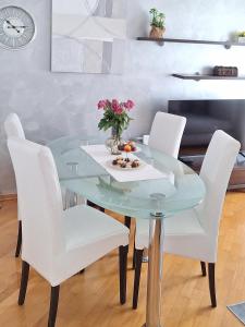 una mesa de cristal con sillas blancas y flores. en Apartment Leona, en Split