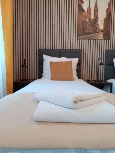 a bed with white sheets and an orange pillow on it at Sleep In Apartament Centrum in Wrocław