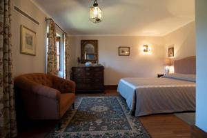 a bedroom with a bed and a chair and a mirror at Quinta de Mourães Casa dos Rododendros in Lever