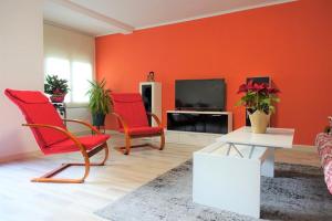 a living room with red chairs and a tv at Apartamento confort I in La Seu d'Urgell