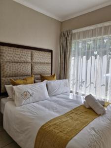 a bedroom with a large white bed with a window at Botle Hive in Kempton Park