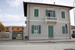 uma casa branca com persianas verdes numa rua em la coccinella em Marina di Pisa