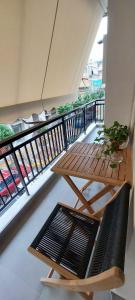 un balcon avec une table en bois, un banc, une table et une plante dans l'établissement On Metro Station Korydallos Apartment, au Pirée