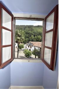 une fenêtre ouverte avec vue sur une maison dans l'établissement Zubietako Ostatua, à Zubieta
