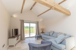 a living room with a blue couch and a tv at Snipe Meadow Barn in Swafield