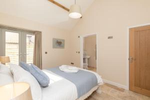 a bedroom with a bed with white sheets and blue pillows at Snipe Meadow Barn in Swafield
