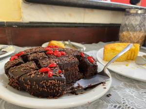 un trozo de pastel de chocolate en un plato con un tenedor en Hotel Roma en São Sebastião