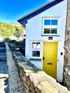 a yellow door on a white house with a window at Little Hillside in Porthtowan