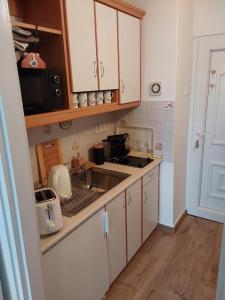 uma cozinha com armários brancos, um lavatório e um micro-ondas em Léna apartman em Fonyód
