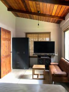 - un salon avec un canapé et une télévision dans l'établissement Cabaña Sabana Redonda, Poás, à Poás