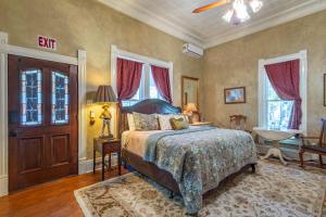 a bedroom with a bed and a table and windows at The Gallery House Boutique Hotel in Stephenville
